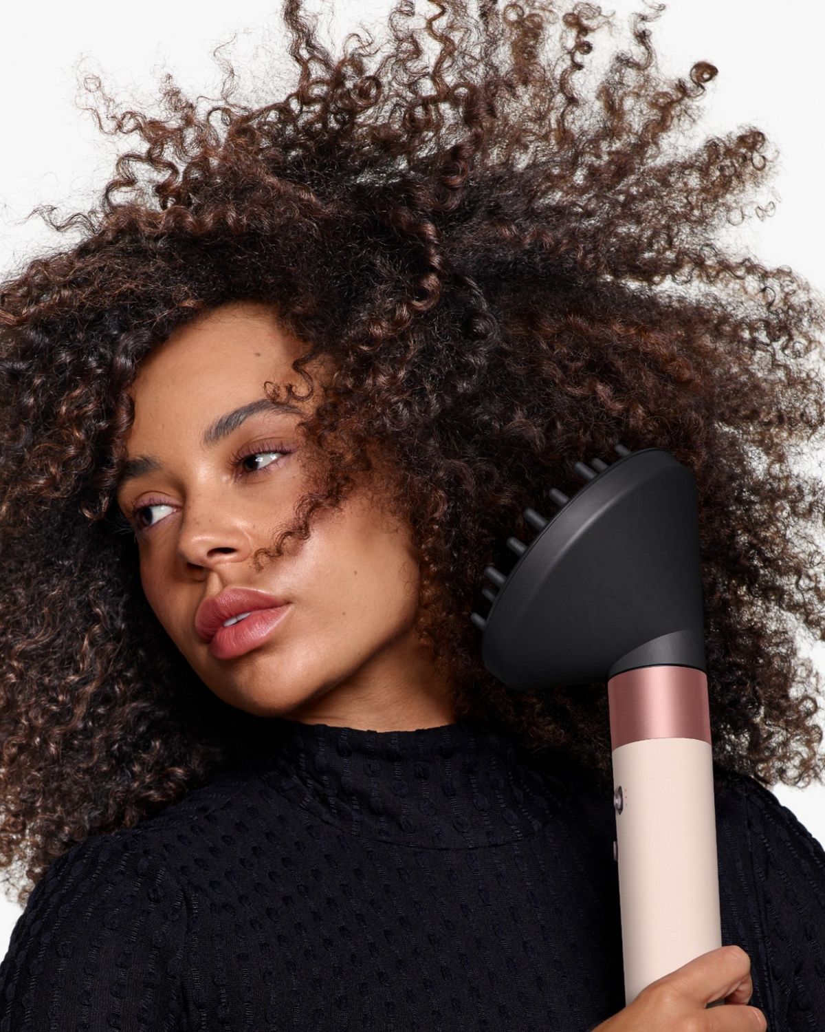 Front-on view of a woman adding volume to her hair with the Dyson Airwrap ID and the Wave+Curl diffuser.
